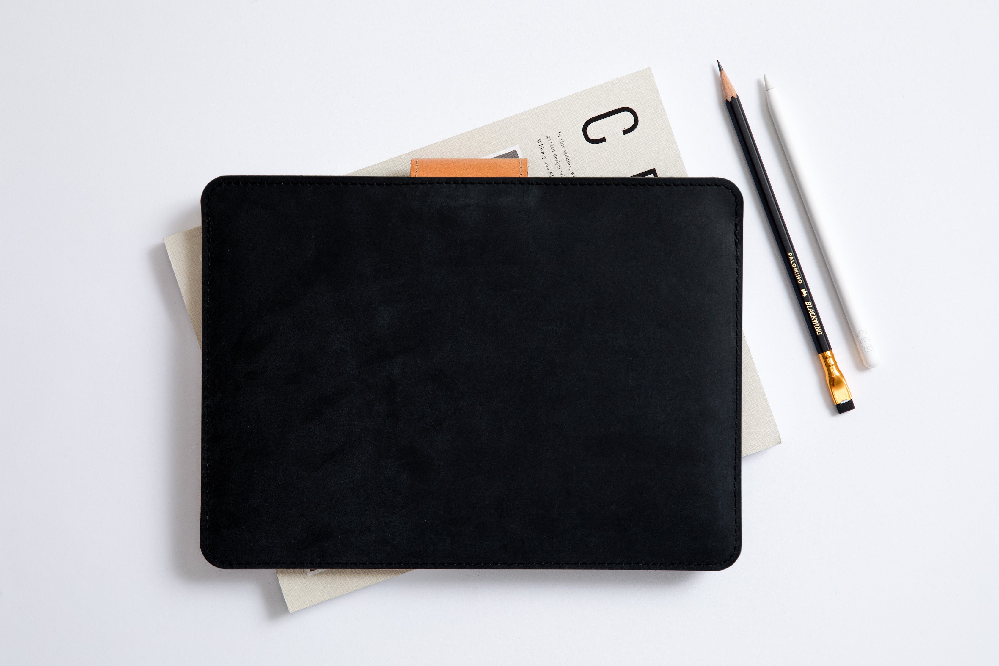 Black leather slim iPad case sleeve with closure.